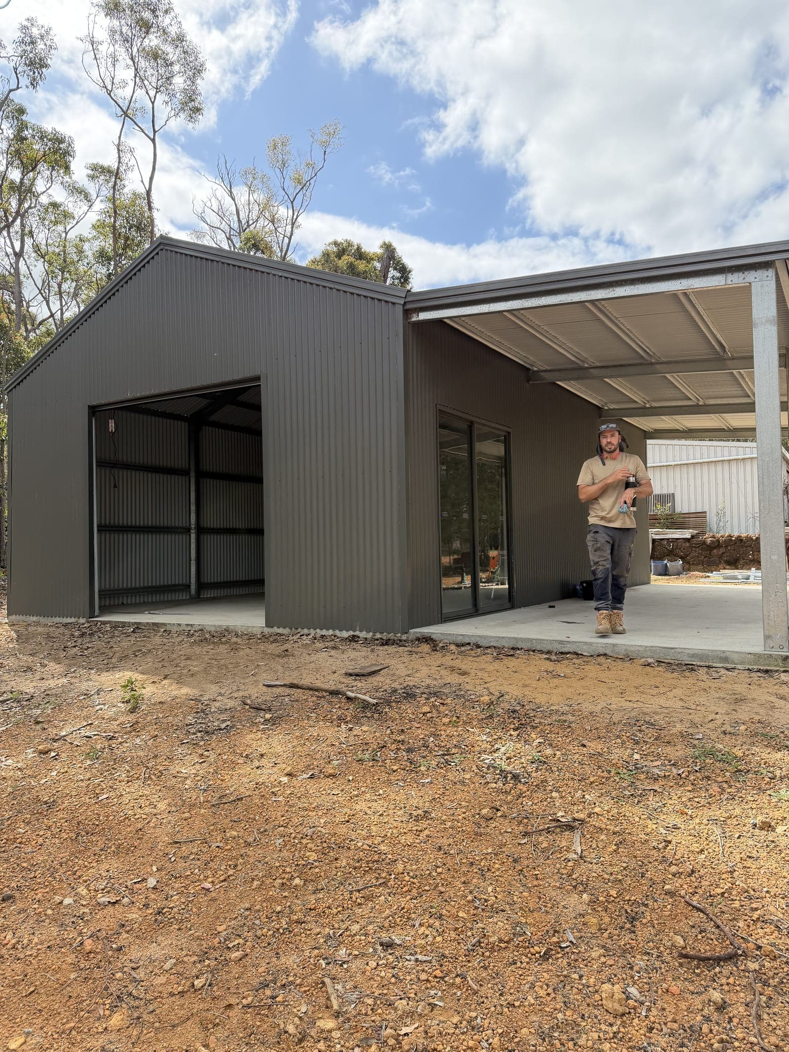 A finished dark steel shed with a covered alfresco and glass sliders