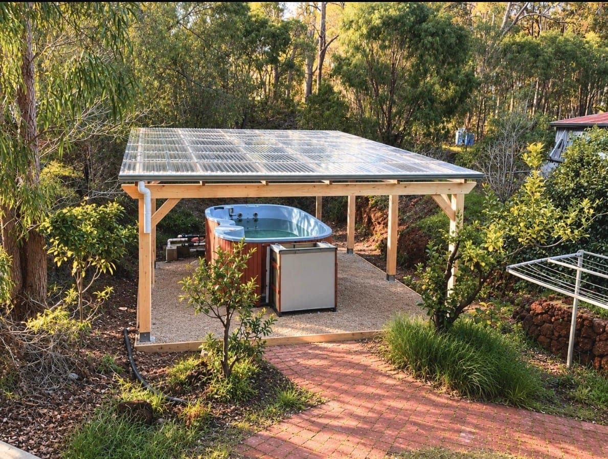 Timber pergola with a clear roof sheltering a swim spa in a bush garden