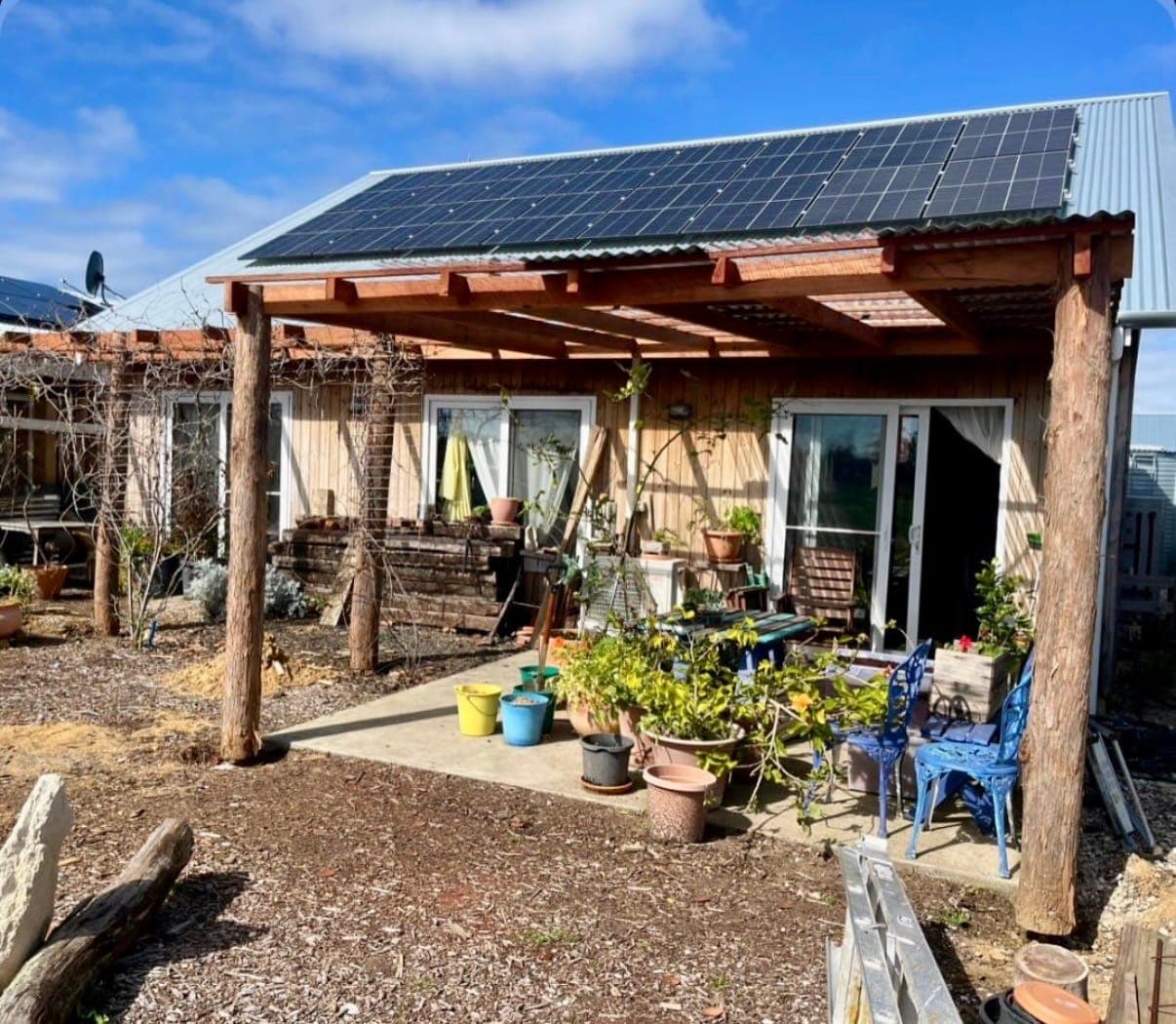 Timber veranda with rough-sawn posts across the front of a house with solar panels